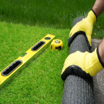 Man's hands spread an artificial turf roll